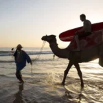 Car rental Agadir airport vehicle parked near the beautiful Taghazout beach, providing easy access for surfers and travelers.